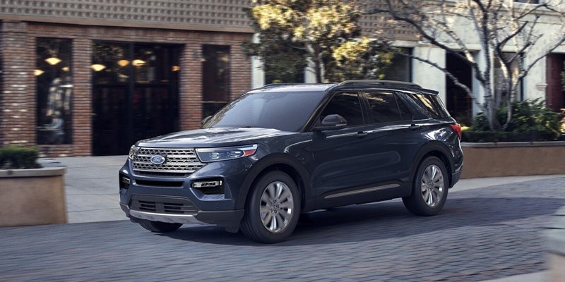 Dark grey Ford Explorer parked at an angle on a brick street with storefronts and trees in the background.