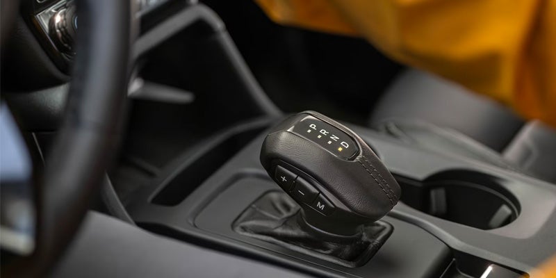 Close-up of a vehicle's automatic gear shifter, with the letters P R N D illuminated, showing it in drive.