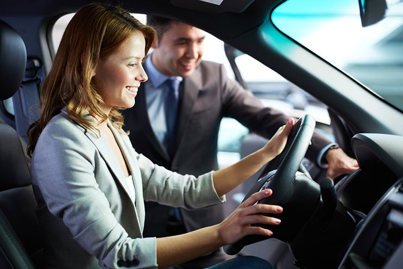 A salesperson communicating with a customer who seating in the car